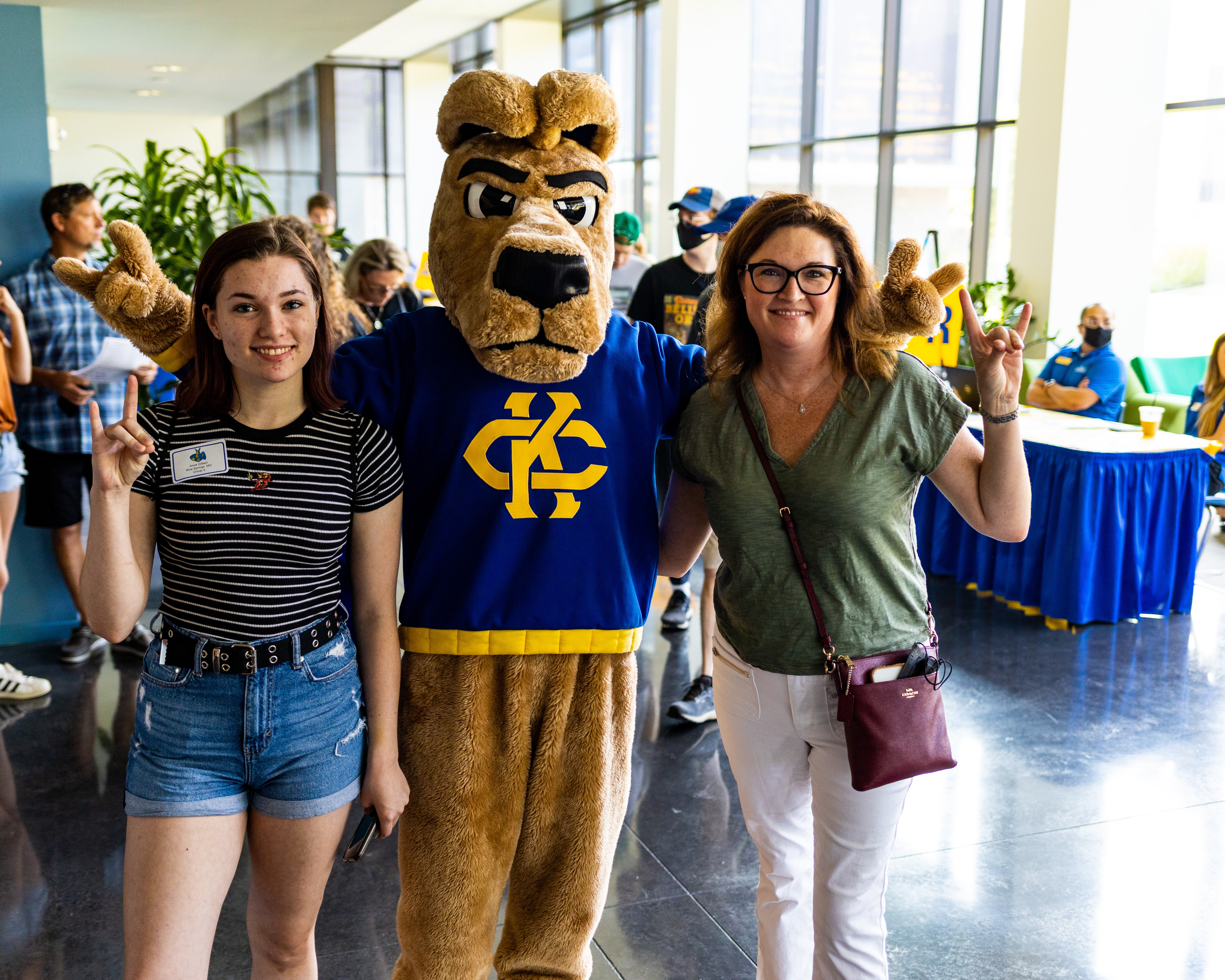 an incoming student and her mother give the roo up hand signal while standing by the KC Roo mascot.