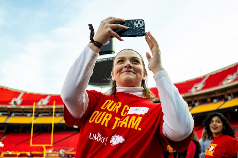 A student takes a selfie while standing on the field during shadow day at the Kansas City Chiefs stadium