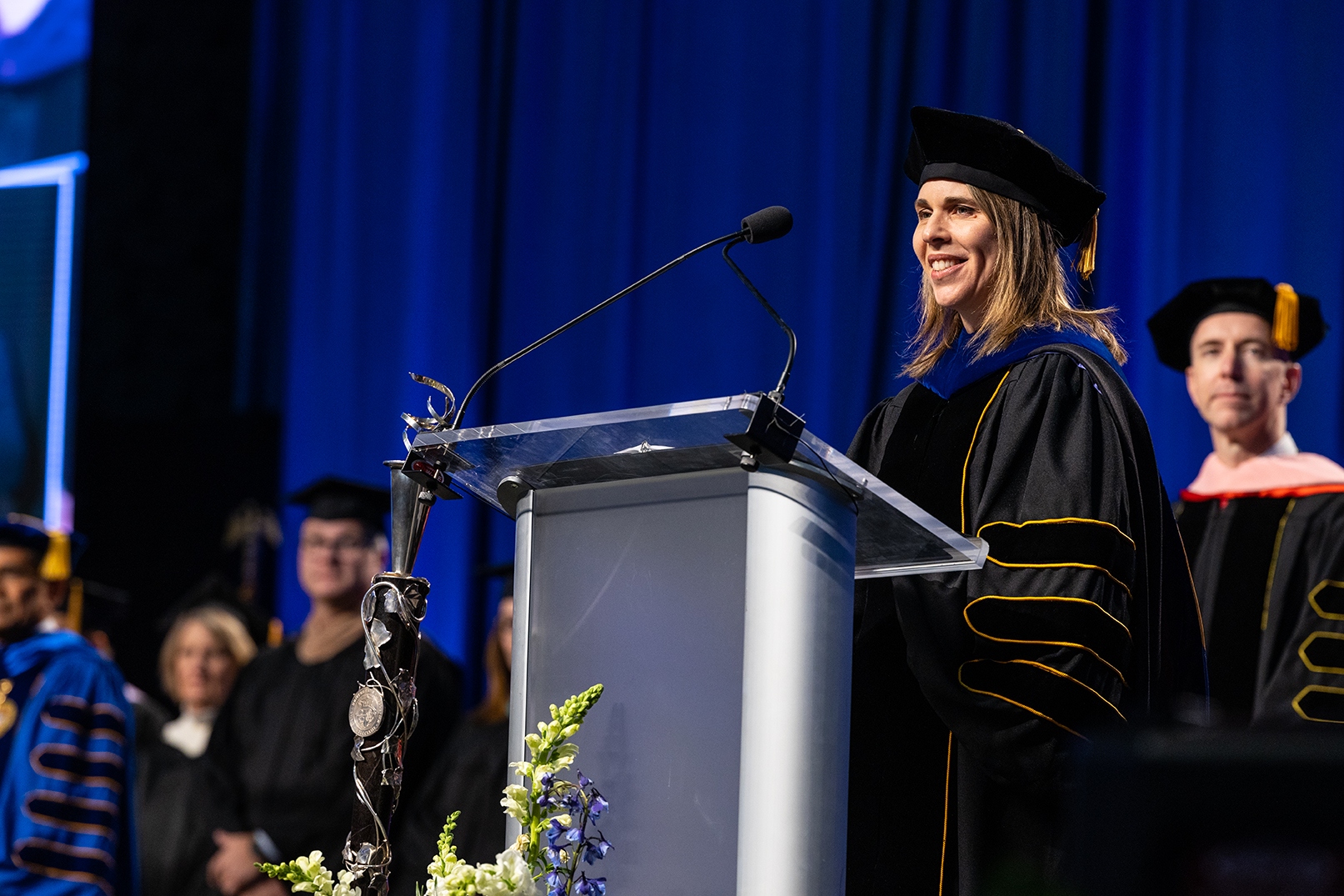 UMKC Provost standing at podium in graduation cap and robes