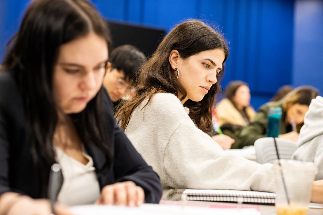a student concentrates while taking notes in a law classroom. 
