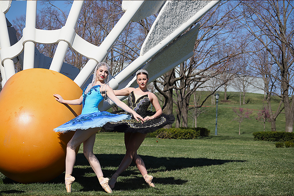 Two ballerinas posing in front of a shuttlecock
