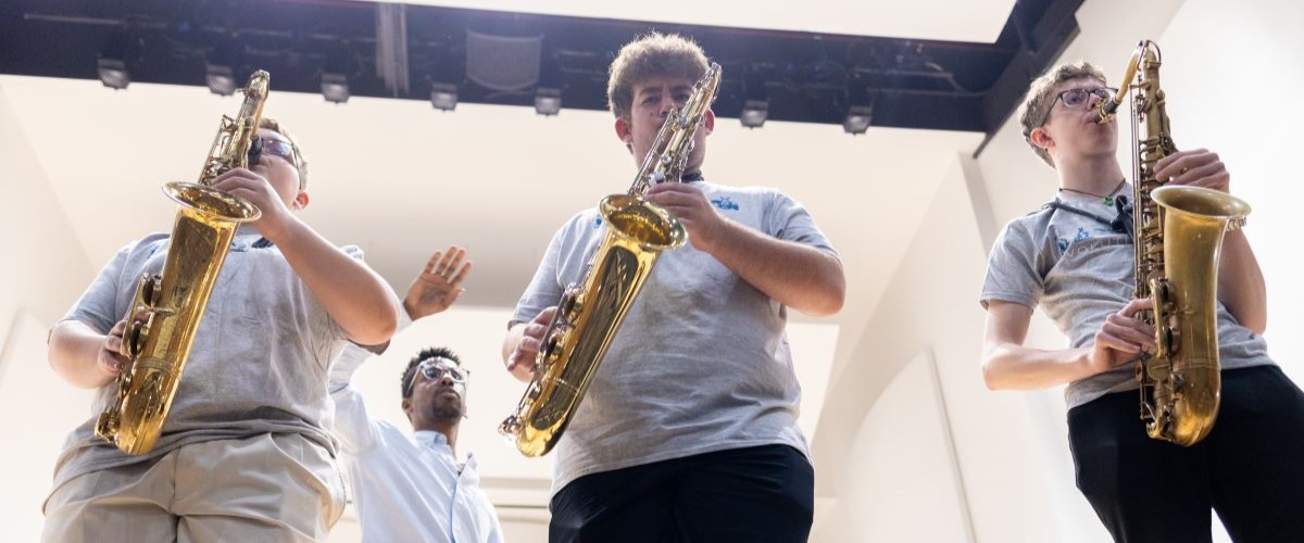 Three Conservatory students play their saxophones in a workshop with an instructor.