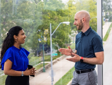 Two staff members talking in a building on campus.