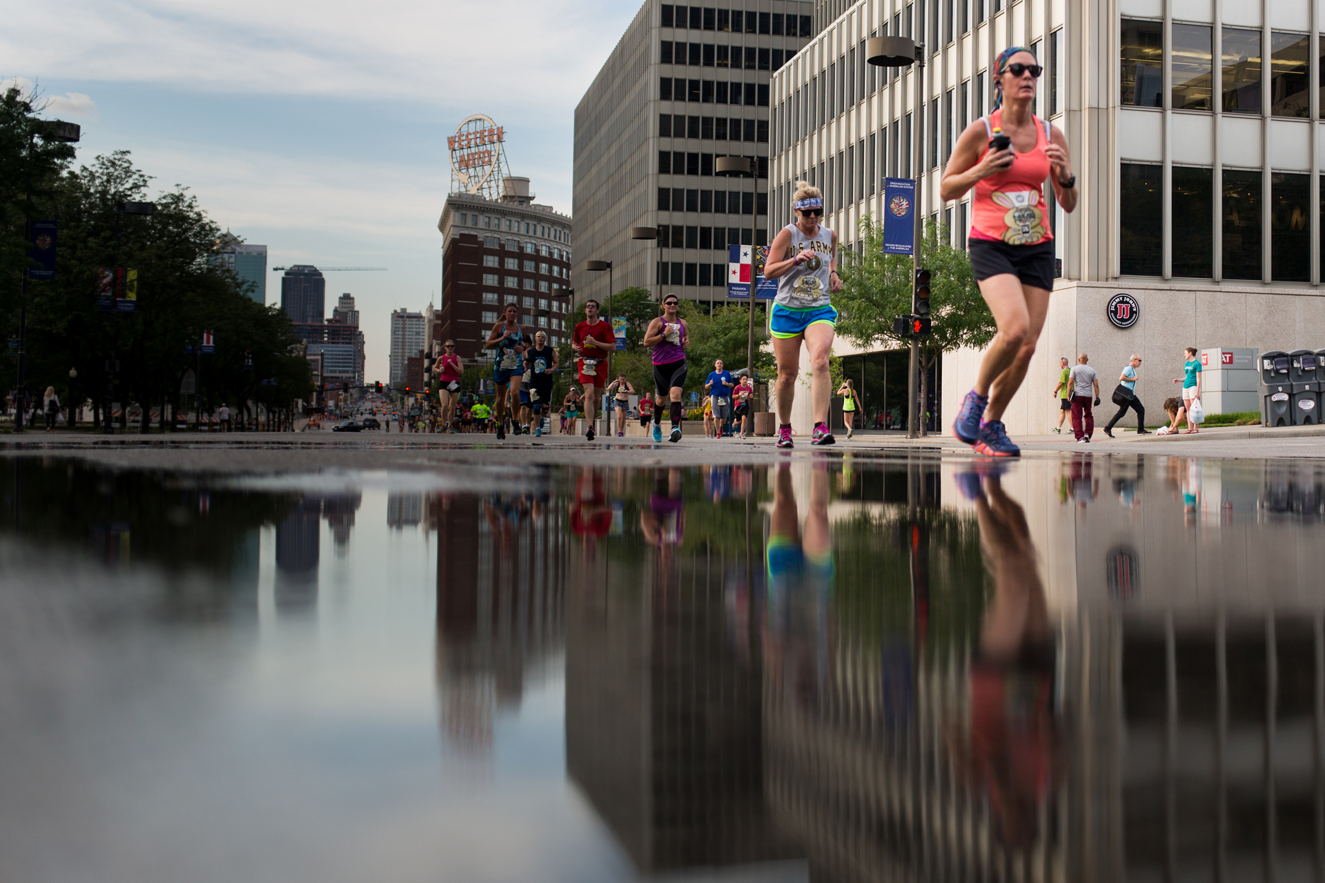 Marathon runners pass by a puddle 