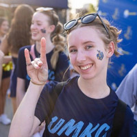 Student gives Roo Up hand sign at soccer game while celebrating on the patio