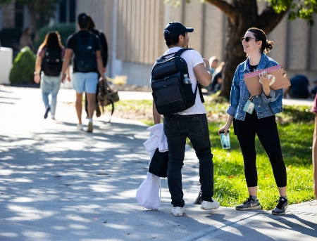 Two students talking on campus walkway in the quad.