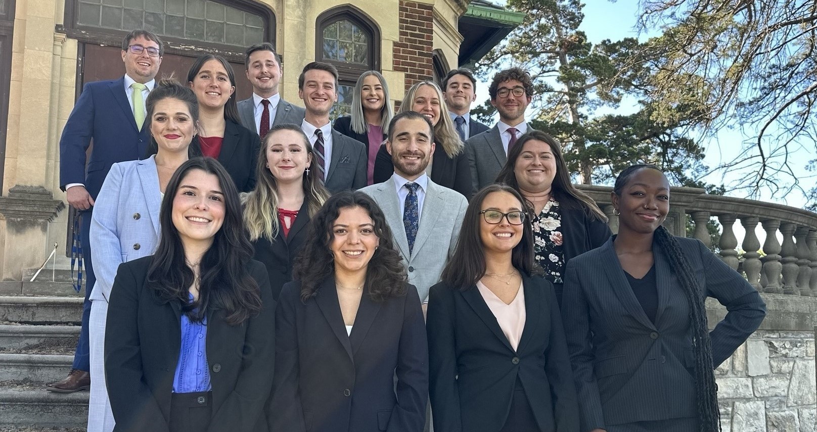 18 members of the Mock trial team stand on the steps in front of a stone building