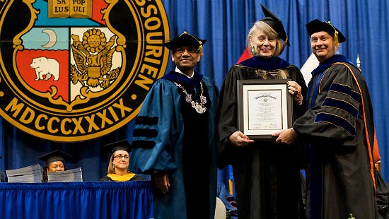 College of Arts and Sciences Dean Wayne Vaught presents Deirdre McCloskey, with a framed honorary doctorate on stage.