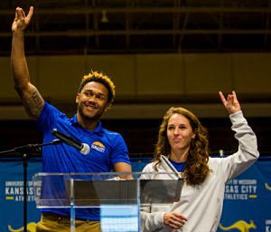 Two UMKC student athletes giving the Roo sign to the audience from the stage