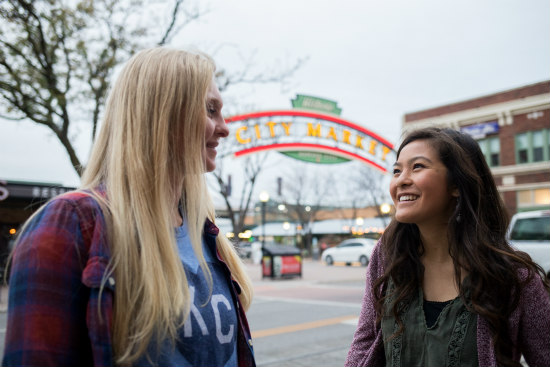 two young women talking outside City Market sign