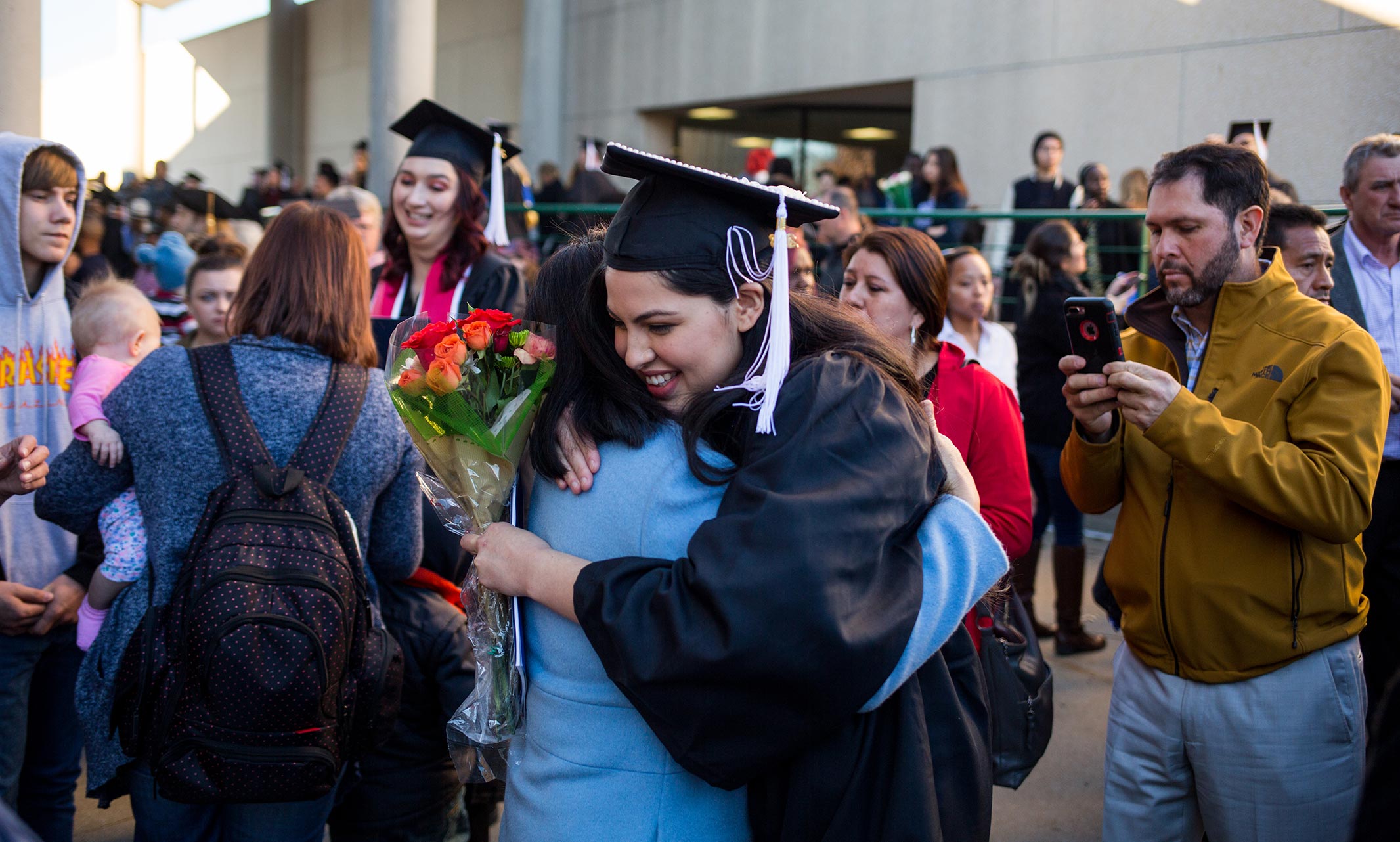 Graduate in cap and gown receiving a congratulatory hug
