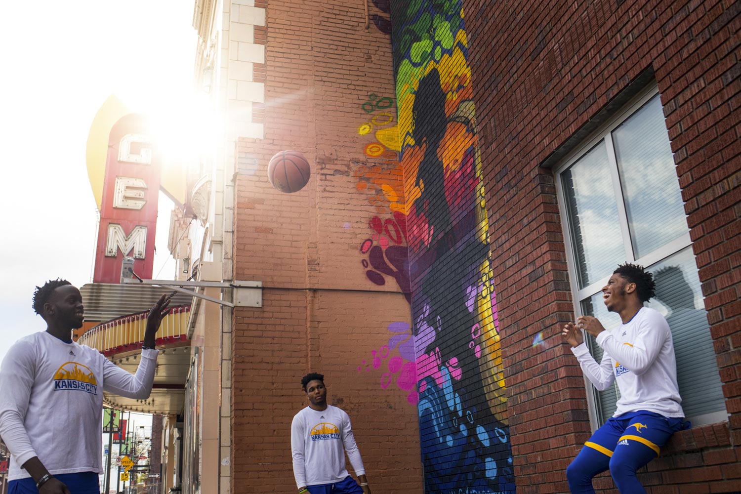 three male basketball players with a ball outside the historic Gem Theater in KC