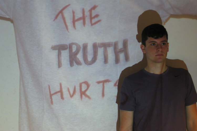 A UMKC School of Medicine student stands in front of a screen that says "The truth hurts."