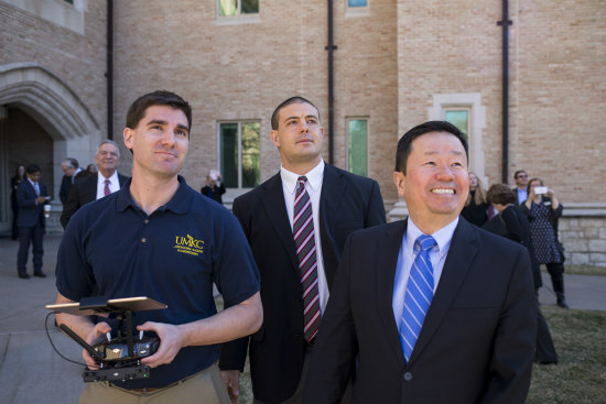 Researchers Travis Fields and Anthony Caruso look at a drone in the sky with UM System President Mun Choi