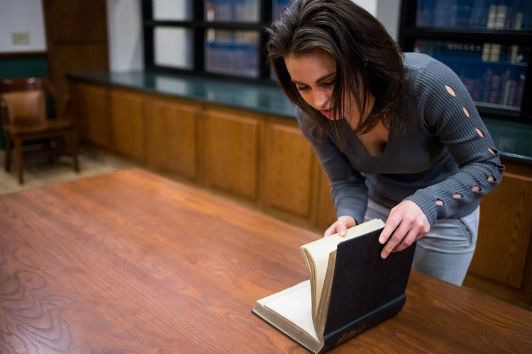 female student skimming library book