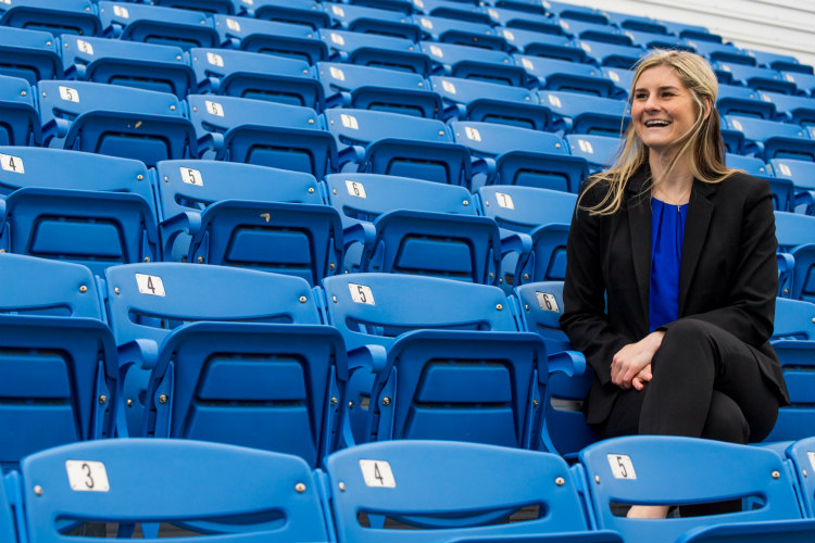 Anna Lillig sits in blue seats at Durwood Stadium at UMKC
