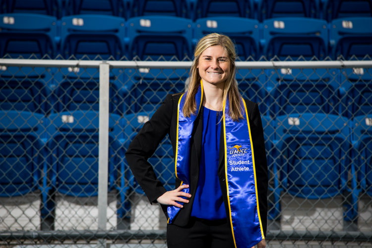 Anna Lillig stands in front of the blue seats of Durwood Stadium