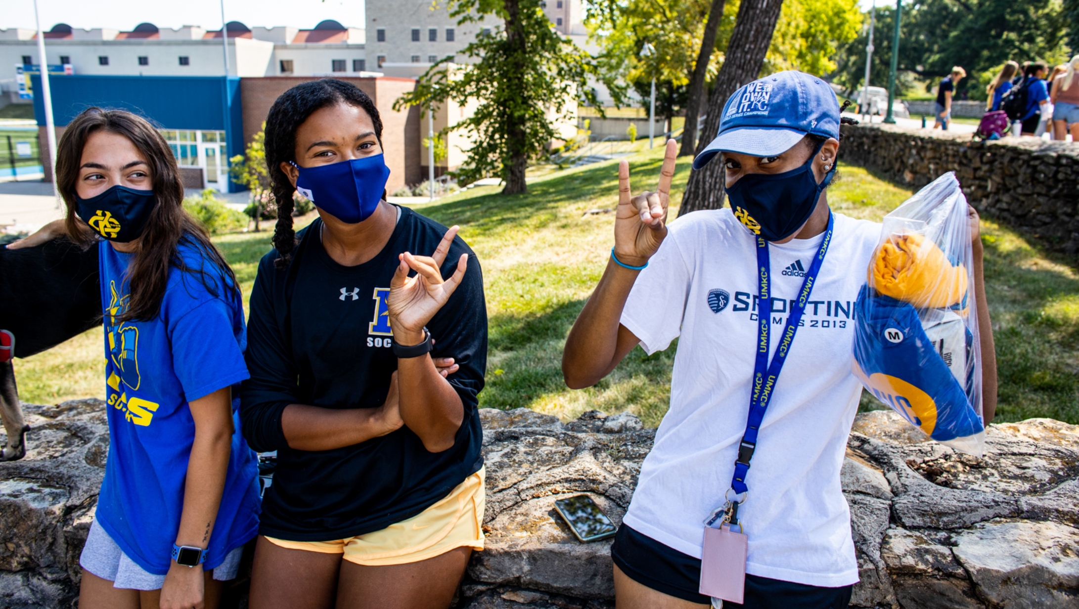 three students in Roo gear doing the Roo hand signal while on campus during first week