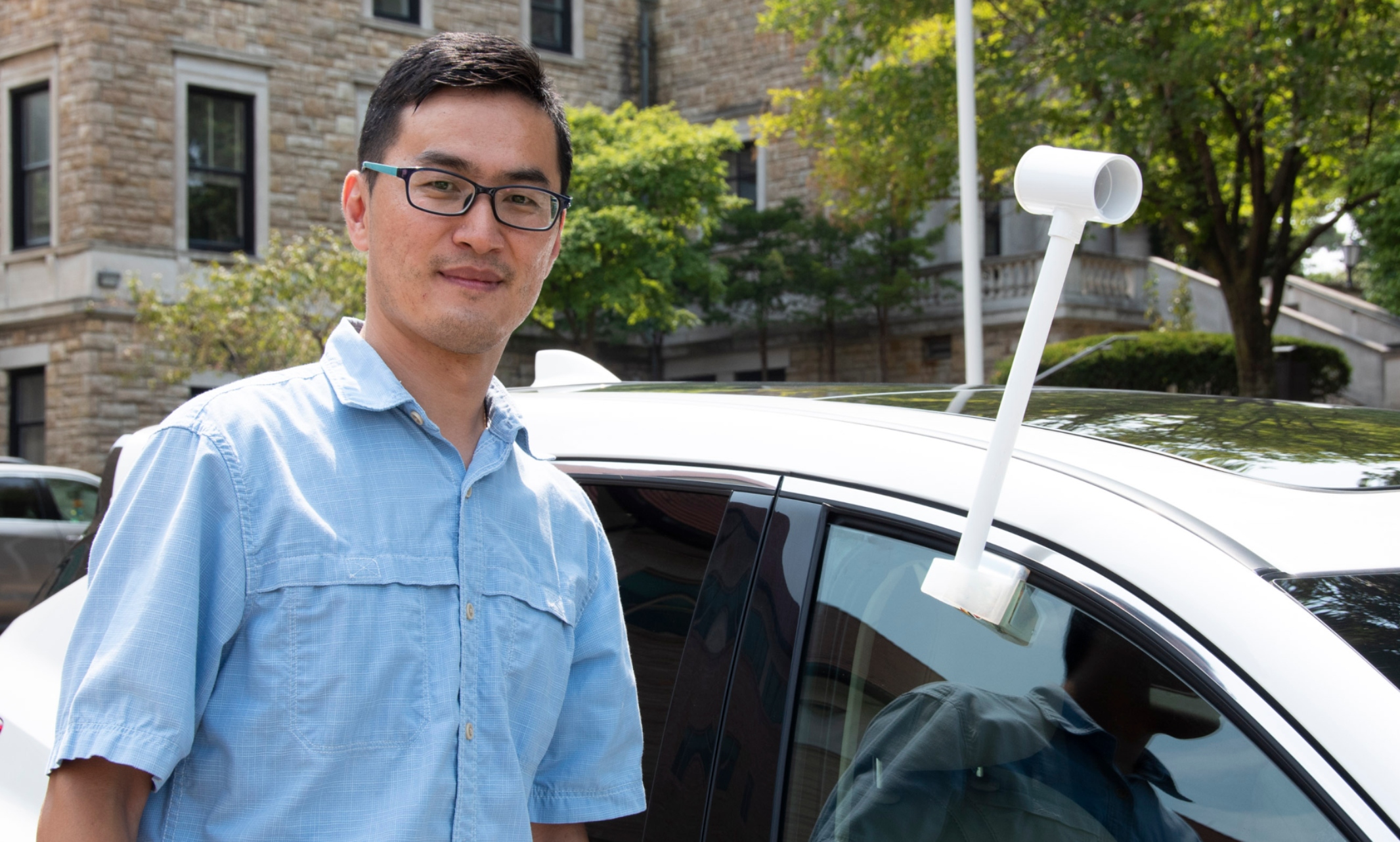 Fengpeng Sun stands next to a car with a heat sensor attached to it