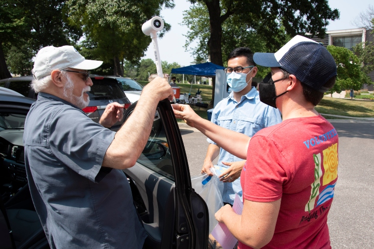 Fengpeng Sun helps a volunteer mount a sensor to a car