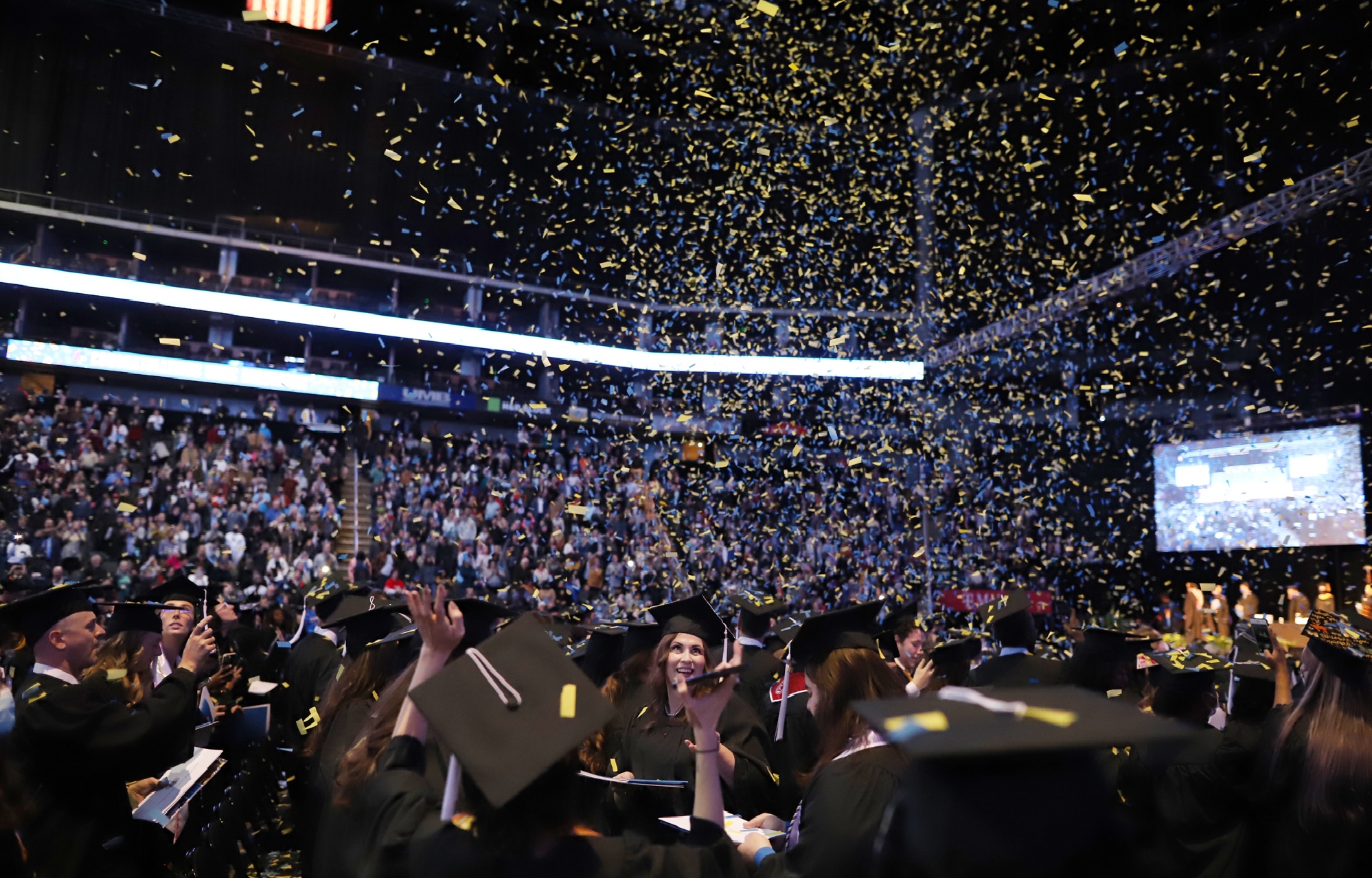 Blue and yellow confetti falls from the ceiling of the T-Mobile Center during UMKC Commencement