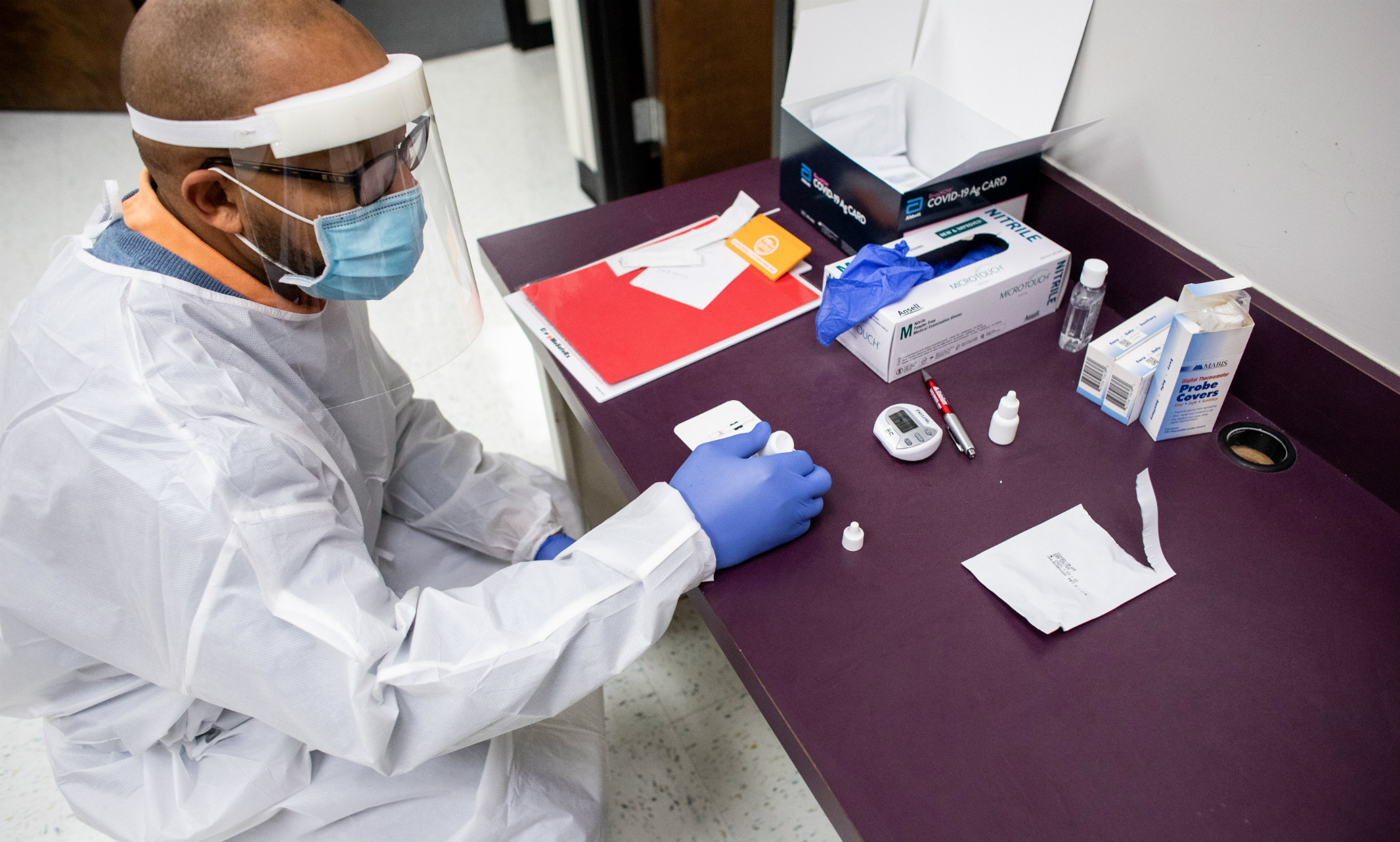 Man in mask and white coat conducting COVID testing in lab.