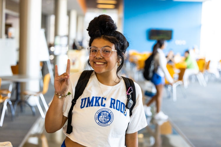 A student smiles with a roo up gesture