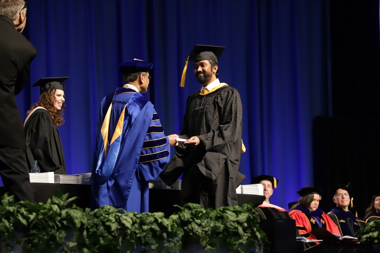 Chancellor Mauli Agrawal hands a graduate a diploma