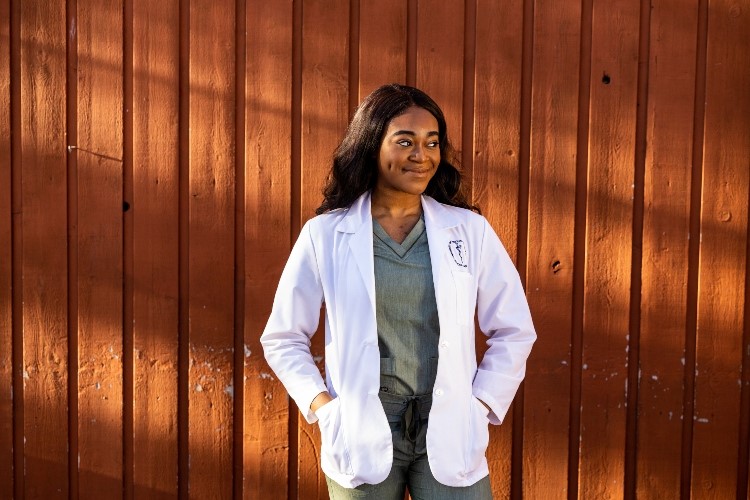 Dubemi Okocha, a student in the accelerated B.A./M.D. program, posing in a white coat