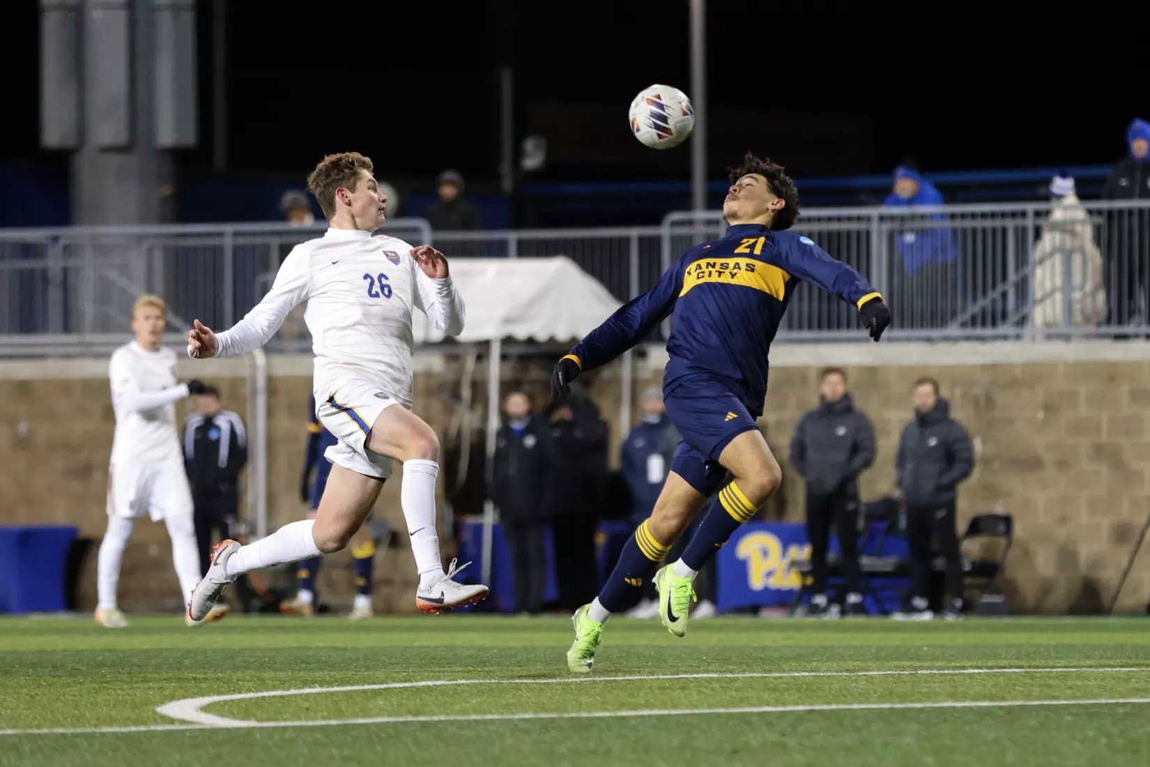 Men's Soccer player and opposing player fight for the ball. 