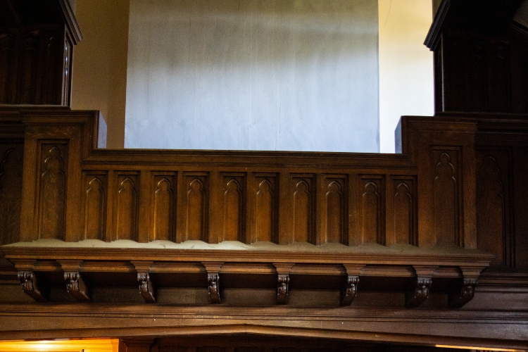 A close up of an organ loft with dark wood panels