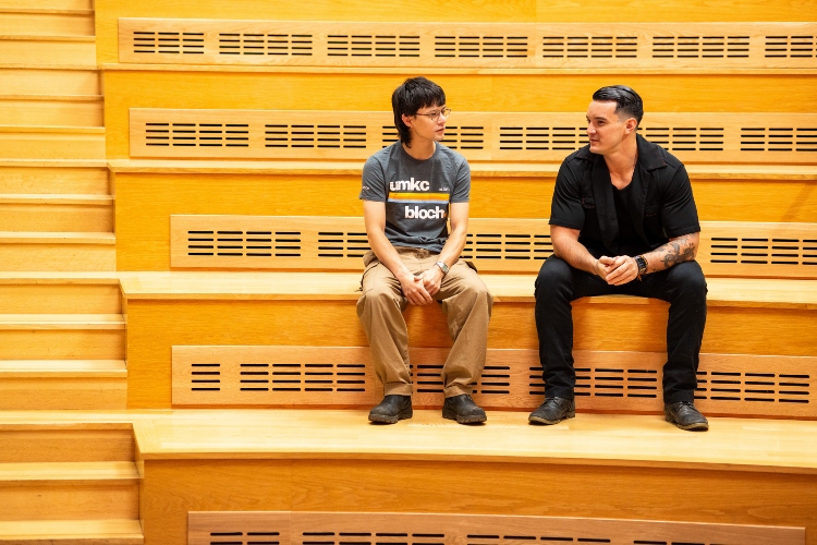 Ga Ji Wang with Charles McGraw sit and chat on the steps inside of Bloch Executive Hall