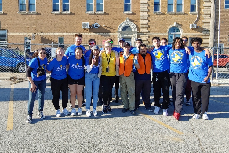 UMKC students stand together smiling for the camera in a parking lot