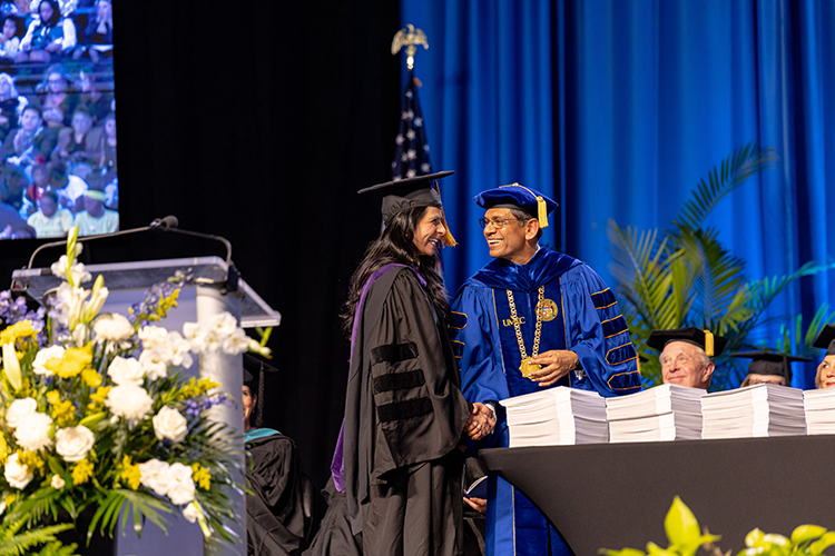 Commencement keynote speaker Mayra Aguirre, president of the Hall Family Foundation, shakes hands with Chancellor Mauli Agrawal. Photo by Derrick Benitz | UMKC