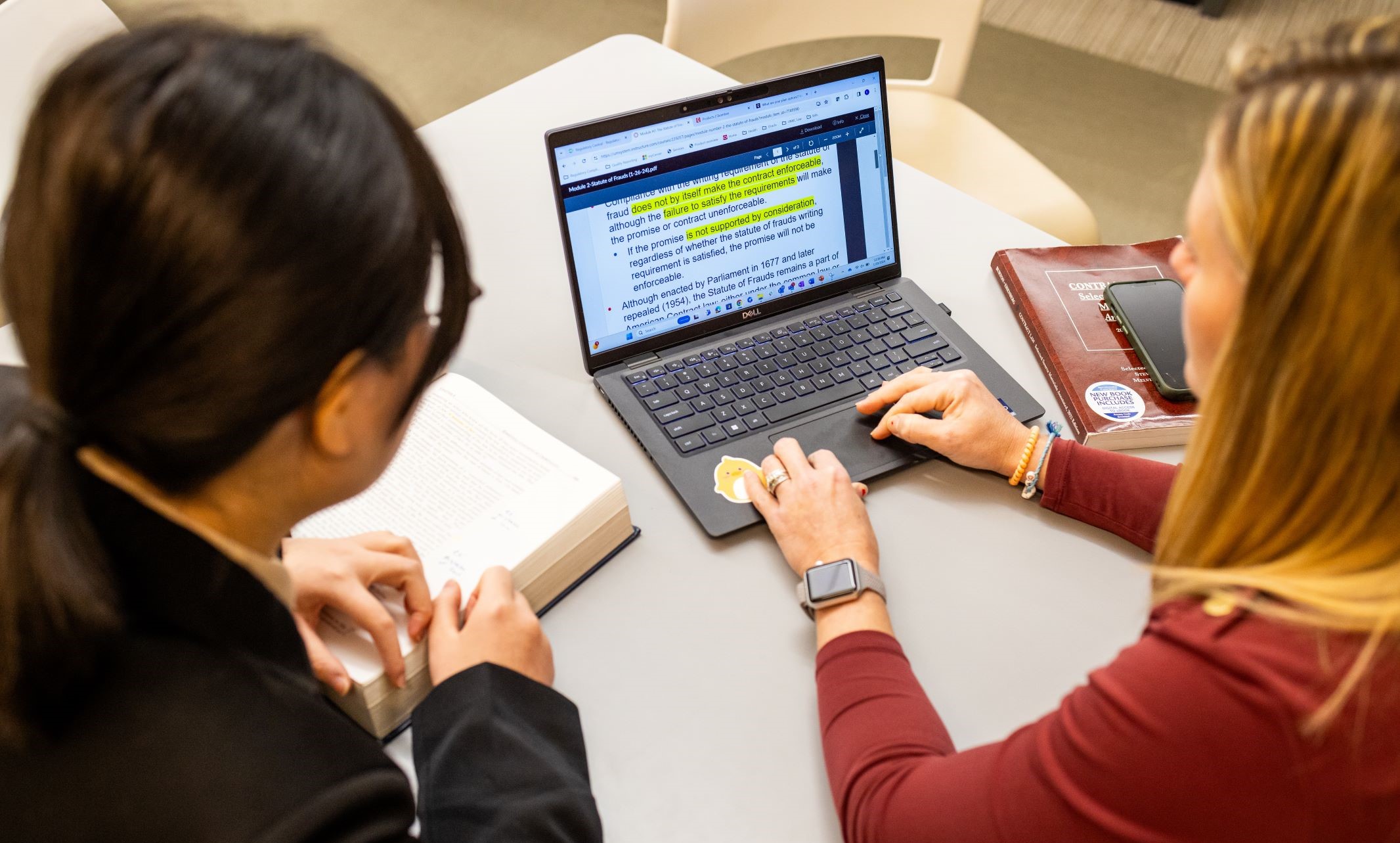 Two students sit together and look at a laptop, studying law terms