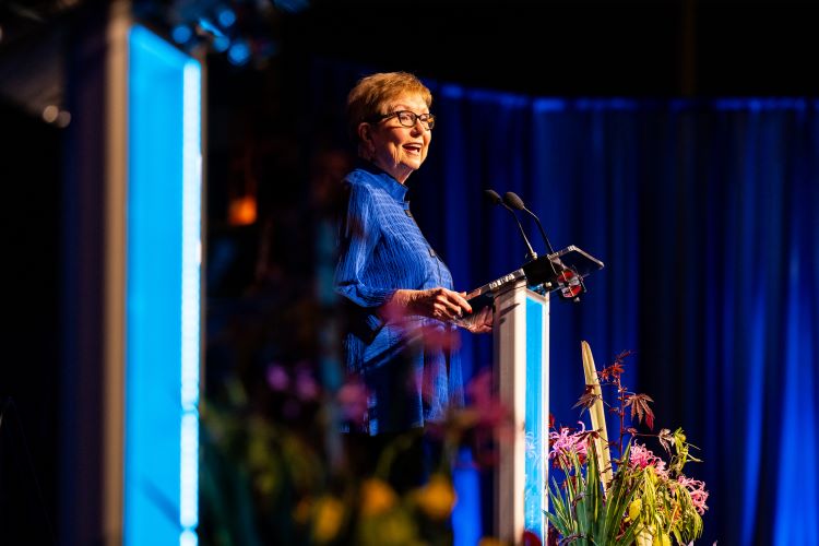 Kay barnes wearing roo blue giving acceptance speech on stage