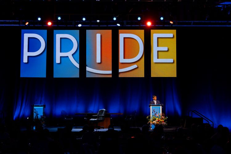 UMKC Chancellor giving a speech on stage with Pride backdrop behind him