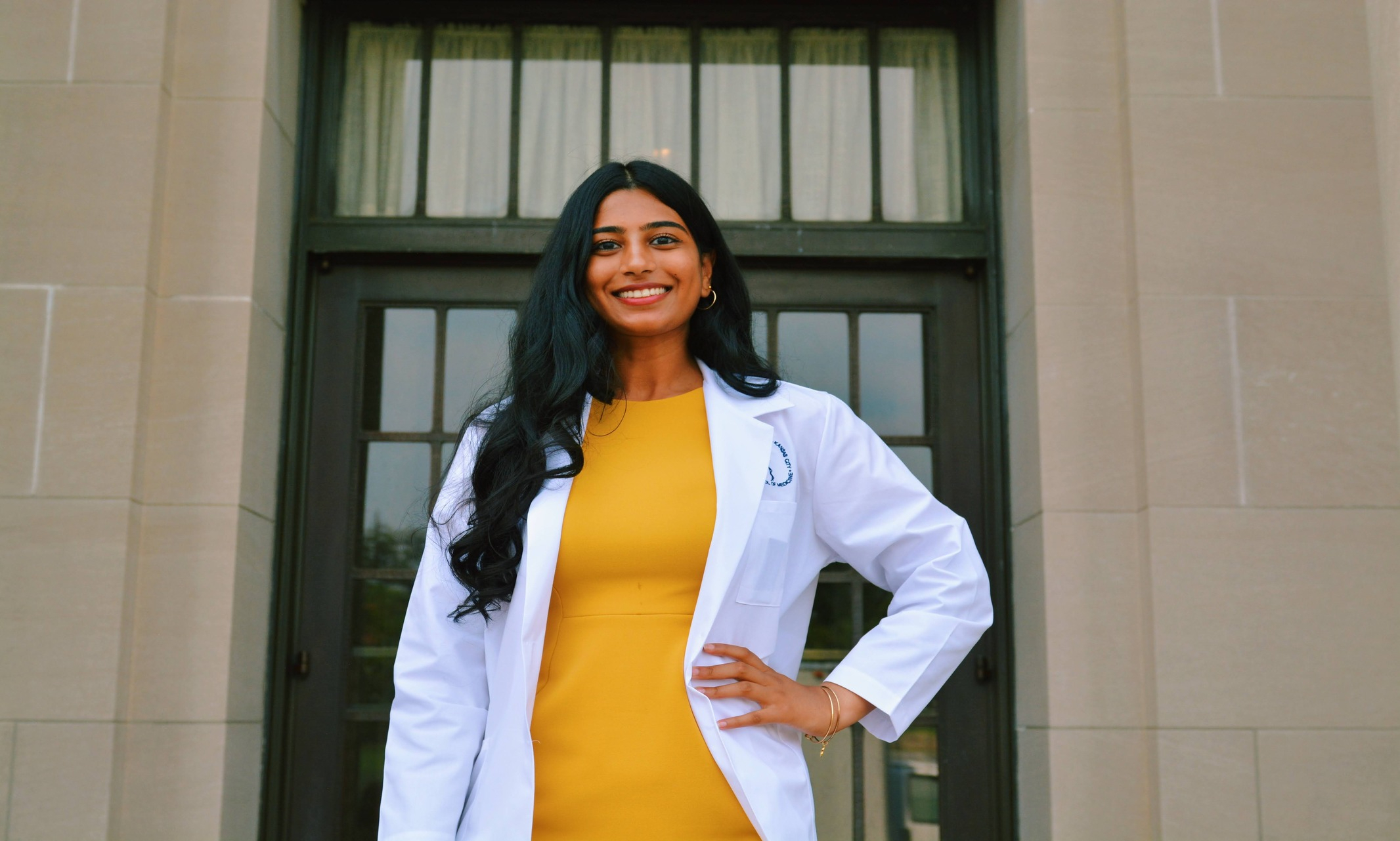 Smiling woman in a yellow dress and white coat