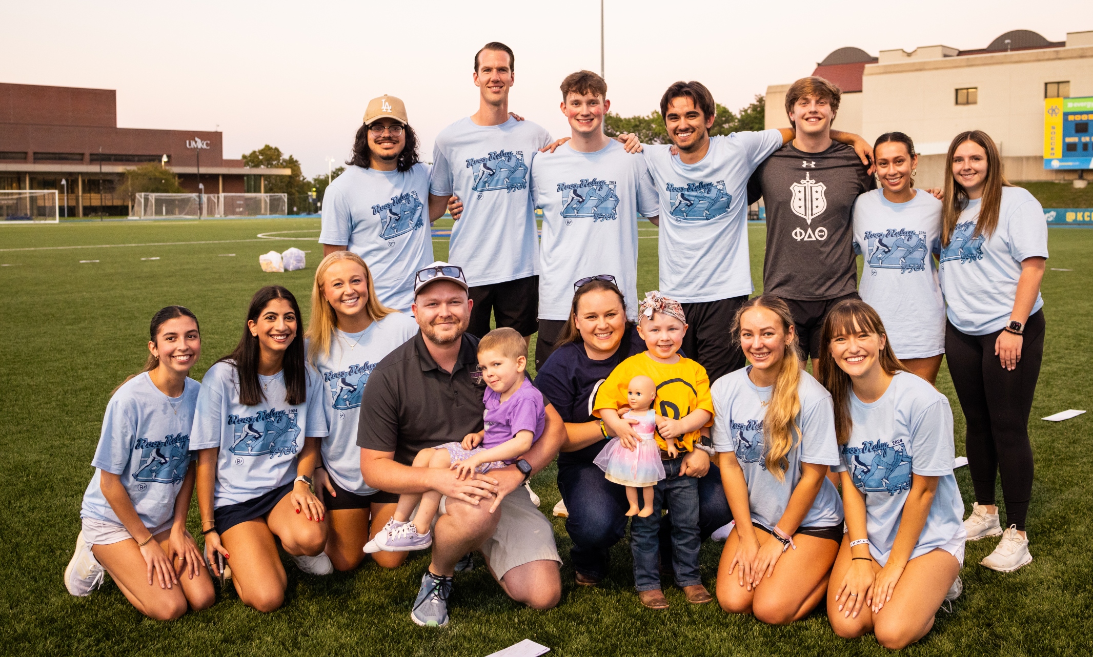 A group of students smiles with Olivia, Brooke and their parents outside at Durwood Stadium