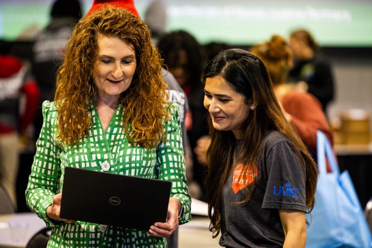 Jennifer and Nisha talking about something on the computer at an IUE event