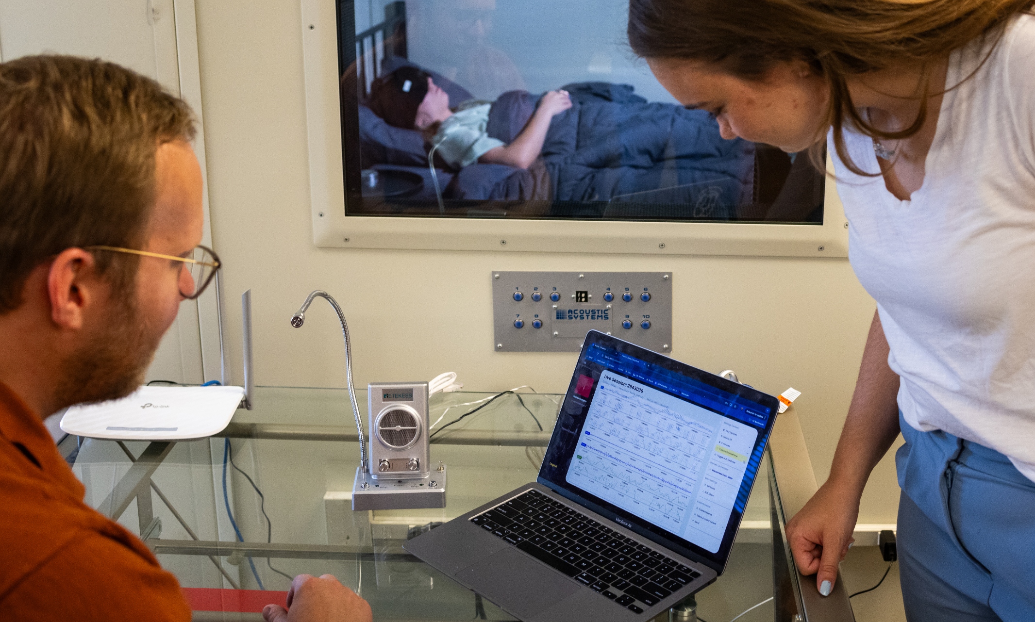 A professor and research student observe another student in the sleep lab.