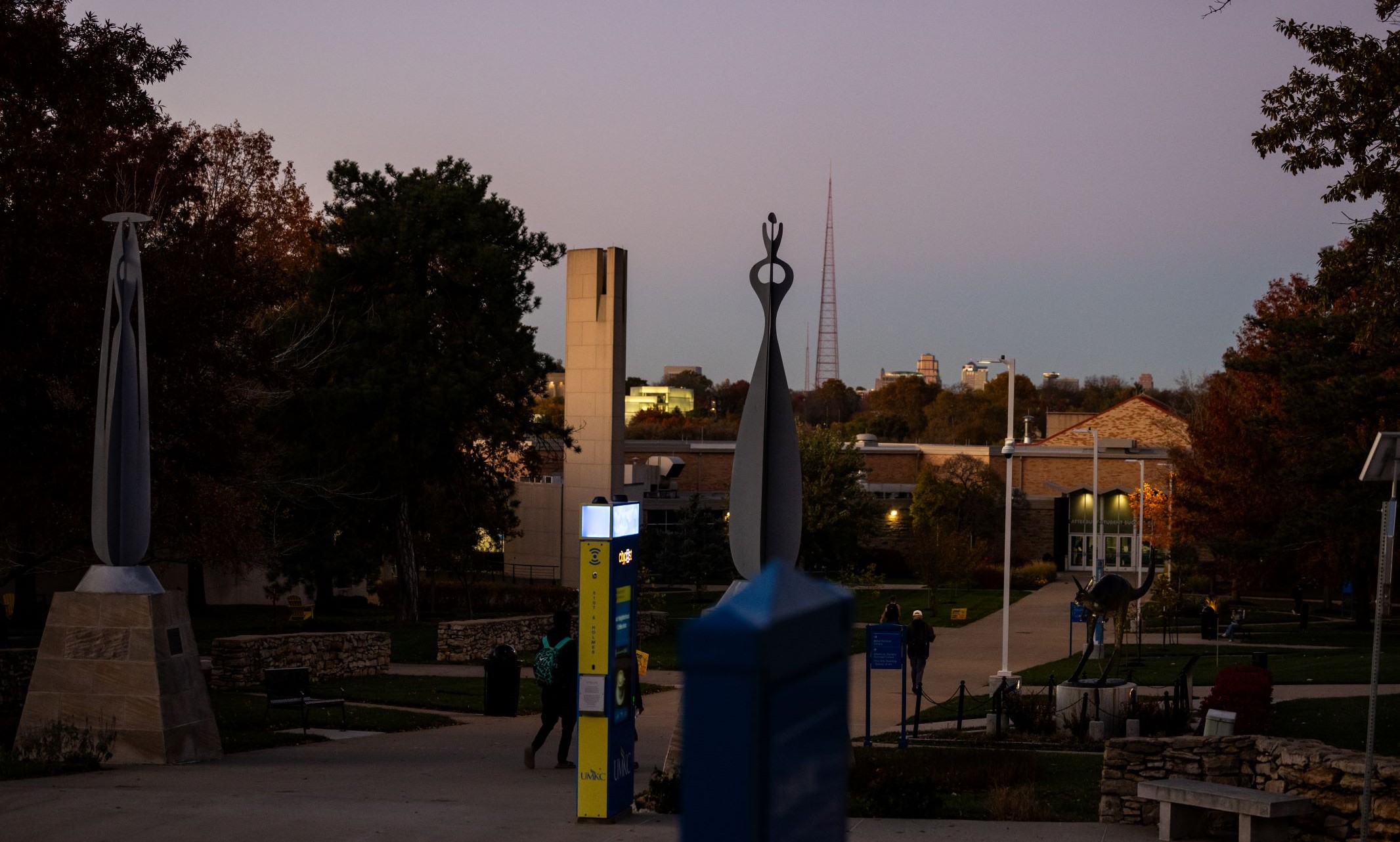 Moon shining over university walkway with students walking toward Atterbury and the kc roo statue is in as well