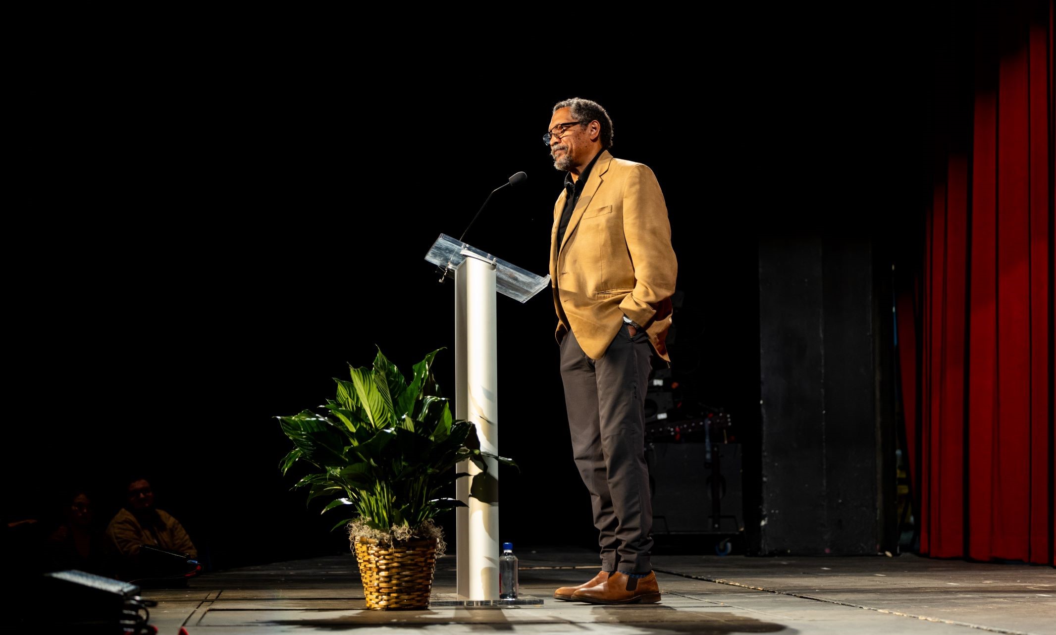 Percival everett on stage wearing yellow jacket behind podium giving speech