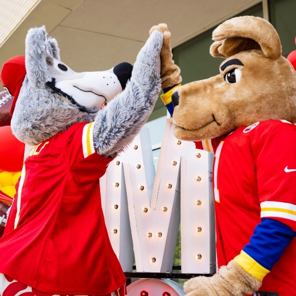 Chiefs' mascot, KC Wolf and UMKC's Roo mascot high five at a joint event.