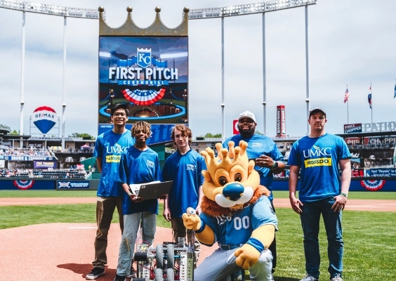 Students stand with robot on field at Kauffman stadium with Slugger