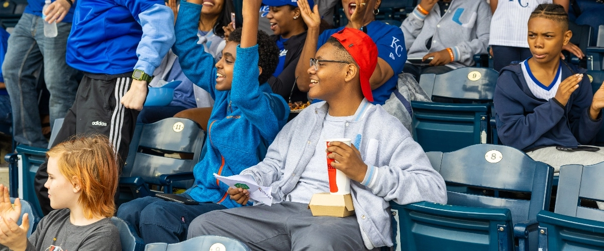 Youth sit in stands at Kauffman Stadium and celebrate at School Day at the K.