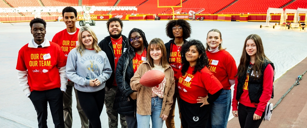 UMKC students taking a group photo while standing on GEHA field at Arrowhead Stadium. 