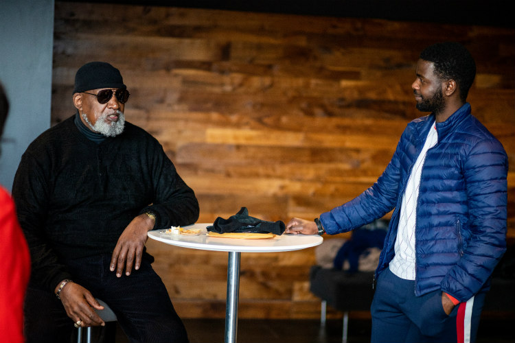 Harry Edwards sitting cool in a chair speaking with male student