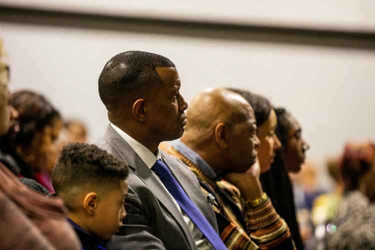 Three generations of men, including athletic director Brandon Martin and son, listening intently to Edwards' lecture